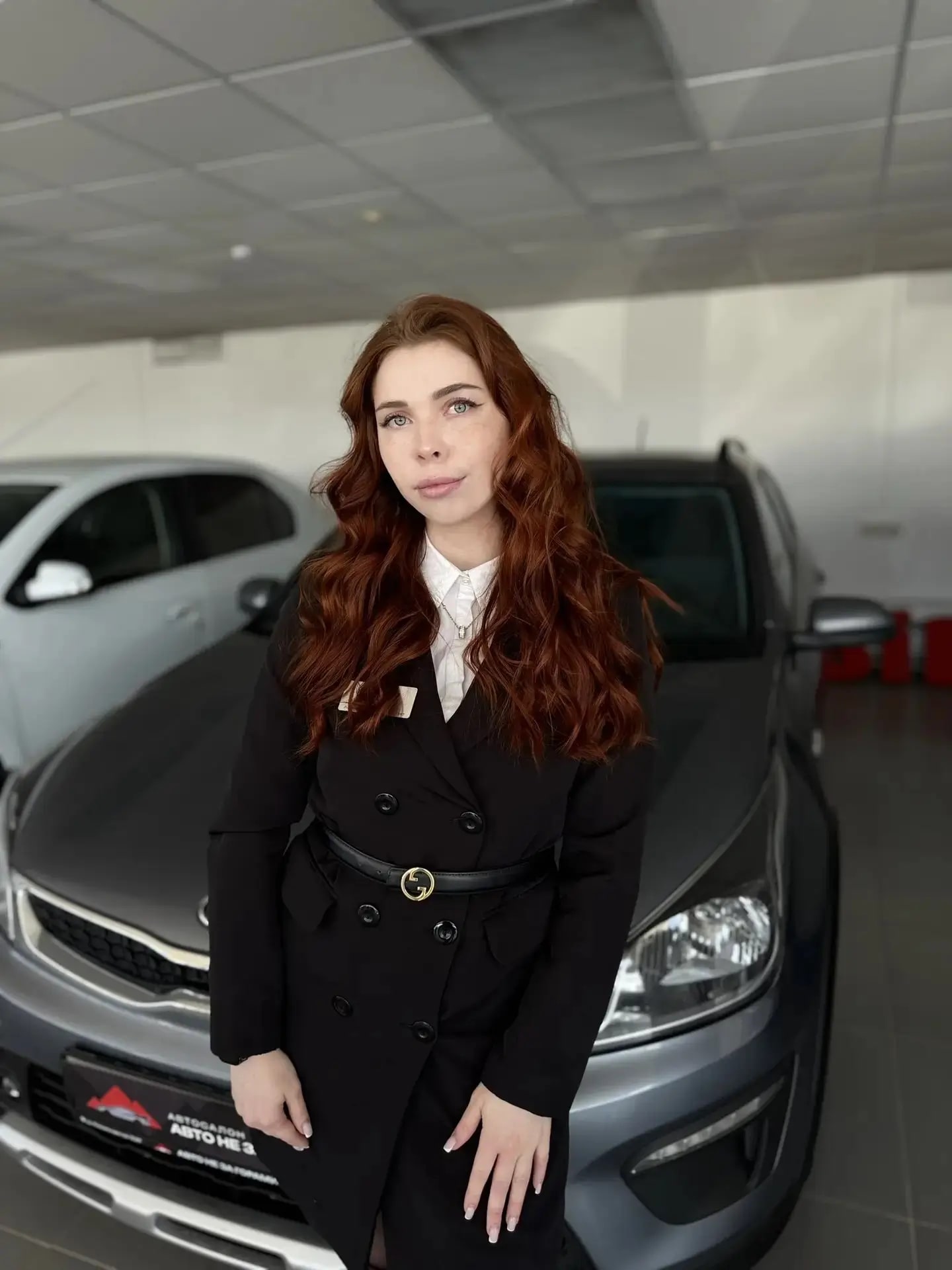 Сотрудница «АвтоКредитРФ» в автосалоне на фоне автомобилей с пробегом